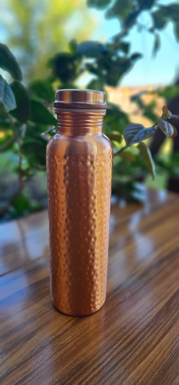 Botella de cobre martillado sobre mesa
